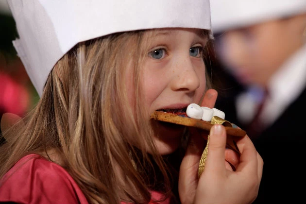 A little girl enjoying an edible Christmas ornament.